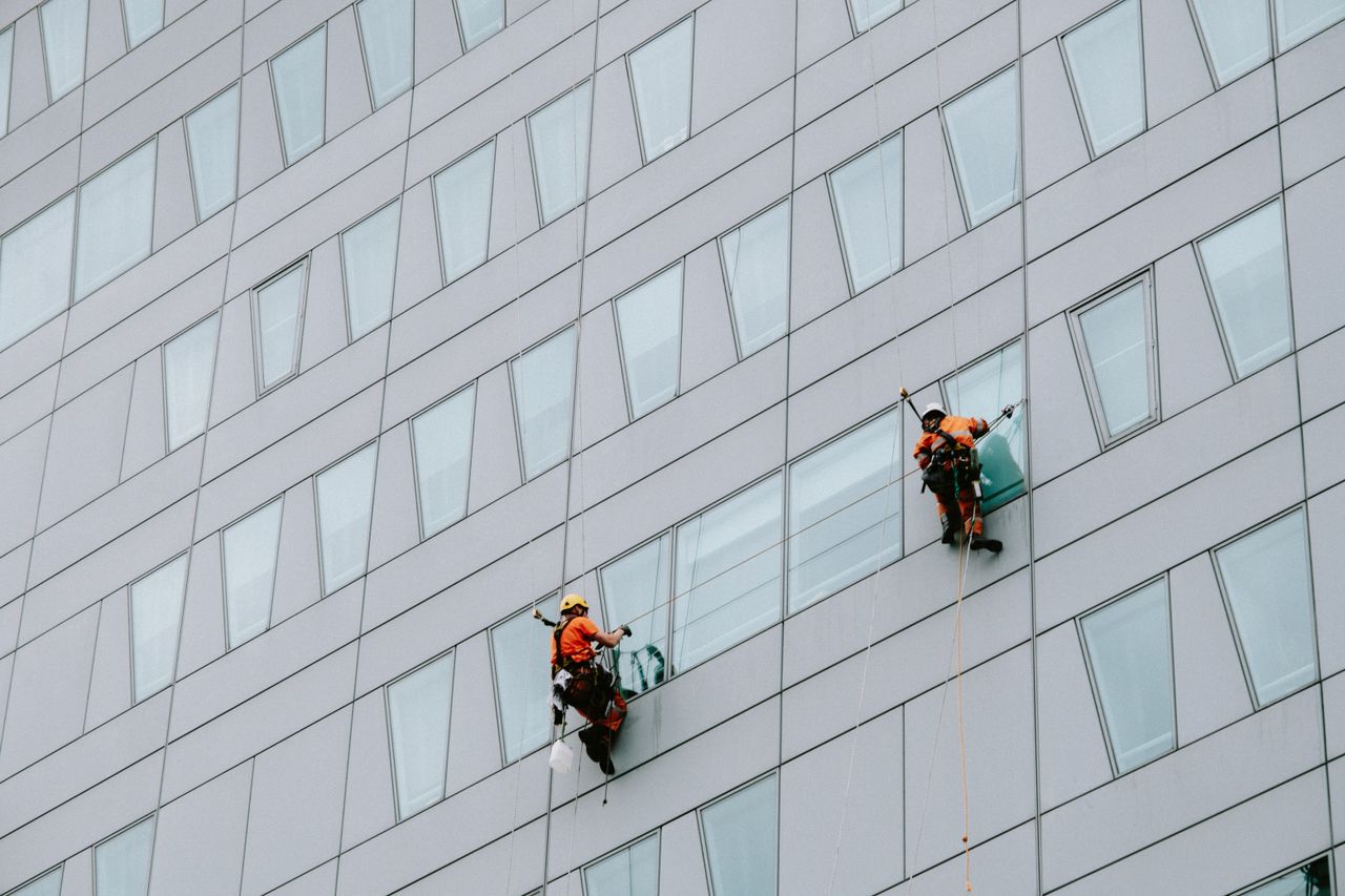 project-02-a High-rise window washers in safety gear cleaning a skyscraper facade.